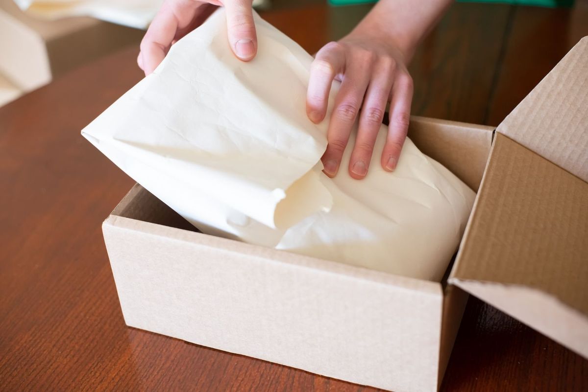 Hands packing an e-commerce order into a cardboard box
